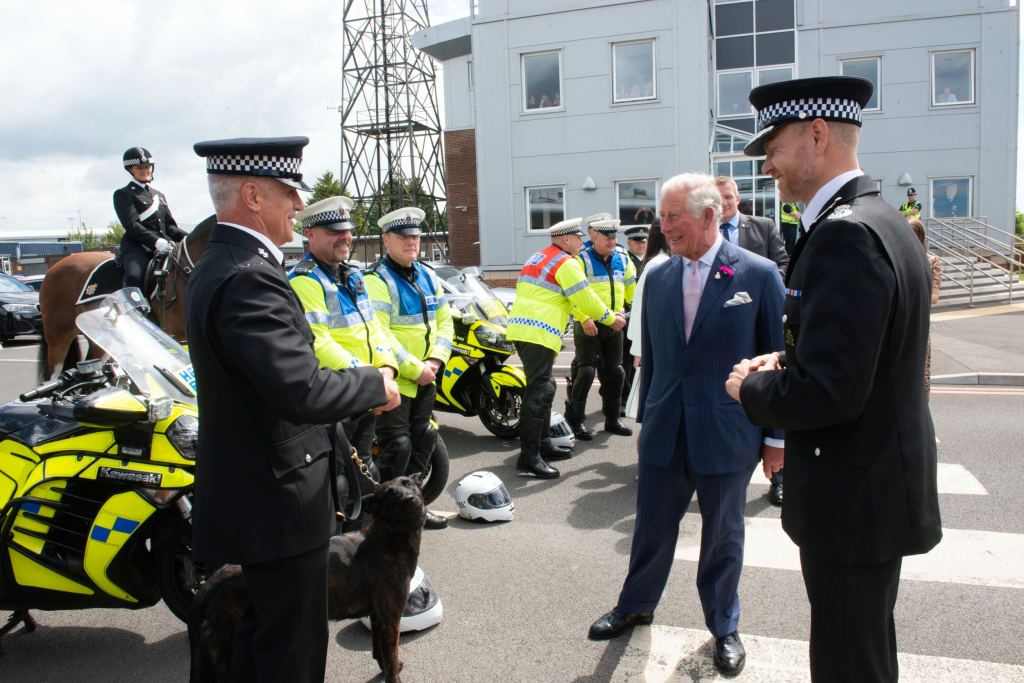 The then-Prince of Wales meets police officers, motorcyclists and a police dog at an outdoor event.