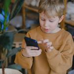 a boy wearing a brown sweater using a smartphone