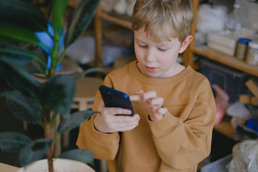 a boy wearing a brown sweater using a smartphone