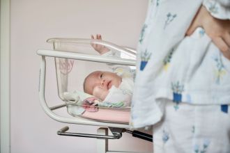 a newborn baby lying in a hospital infant bassinet