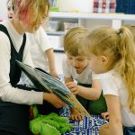 children in the school reading a book with a teacher