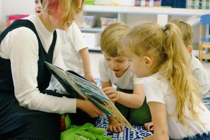 children in the school reading a book with a teacher