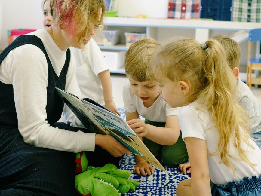 children in the school reading a book with a teacher