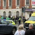 Police officers, some in armed-response gear, and a Welsh Ambulance Service crew behind a cordon on St Helen's Road near the YMCA in Swansea.