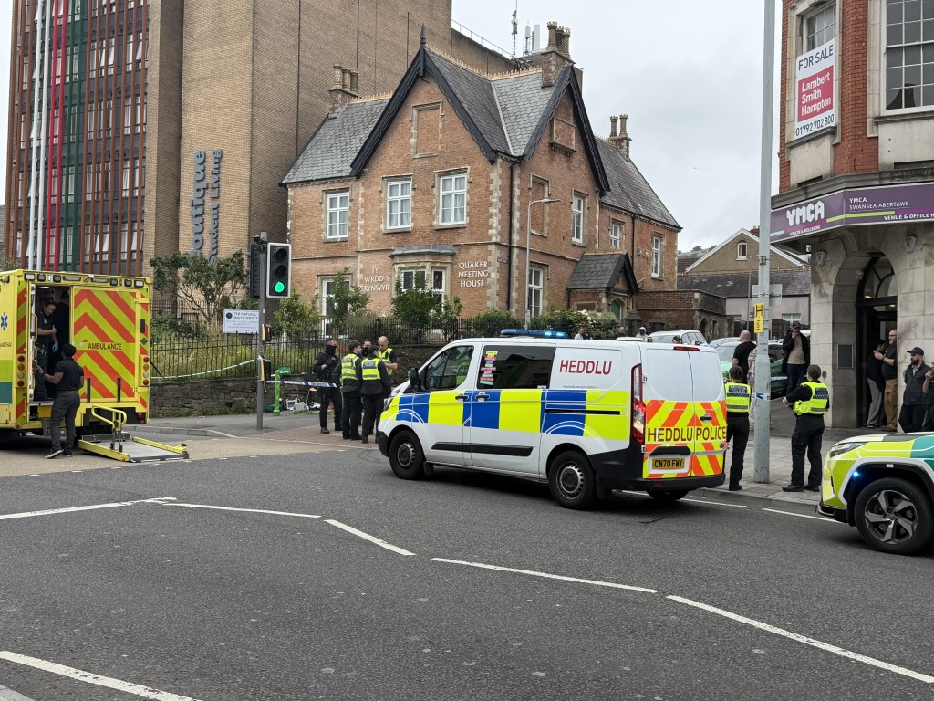 A South Wales Police van and an ambulance beside a taped-off cordon on St Helen's Road, with the Quaker Meeting House behind.