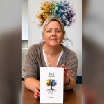 Tammy Allen holding a copy of her poetry collection Roots