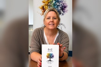 Tammy Allen holding a copy of her poetry collection Roots