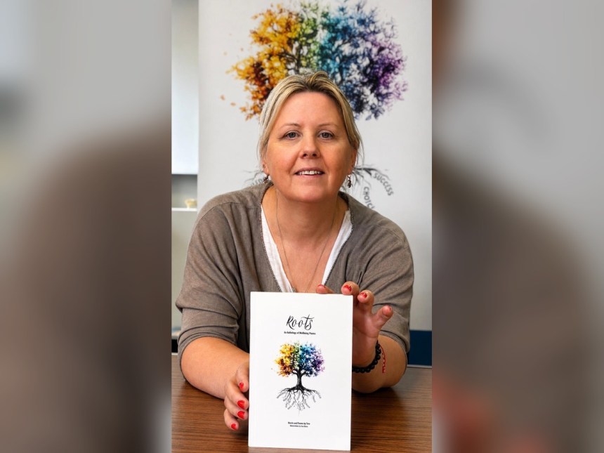 Tammy Allen holding a copy of her poetry collection Roots