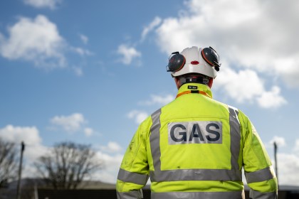 A gas worker in a white hard hat and yellow hi-vis jacket marked GAS, seen from behind (Image: Matthew Horwood / Wales & West Utilities)