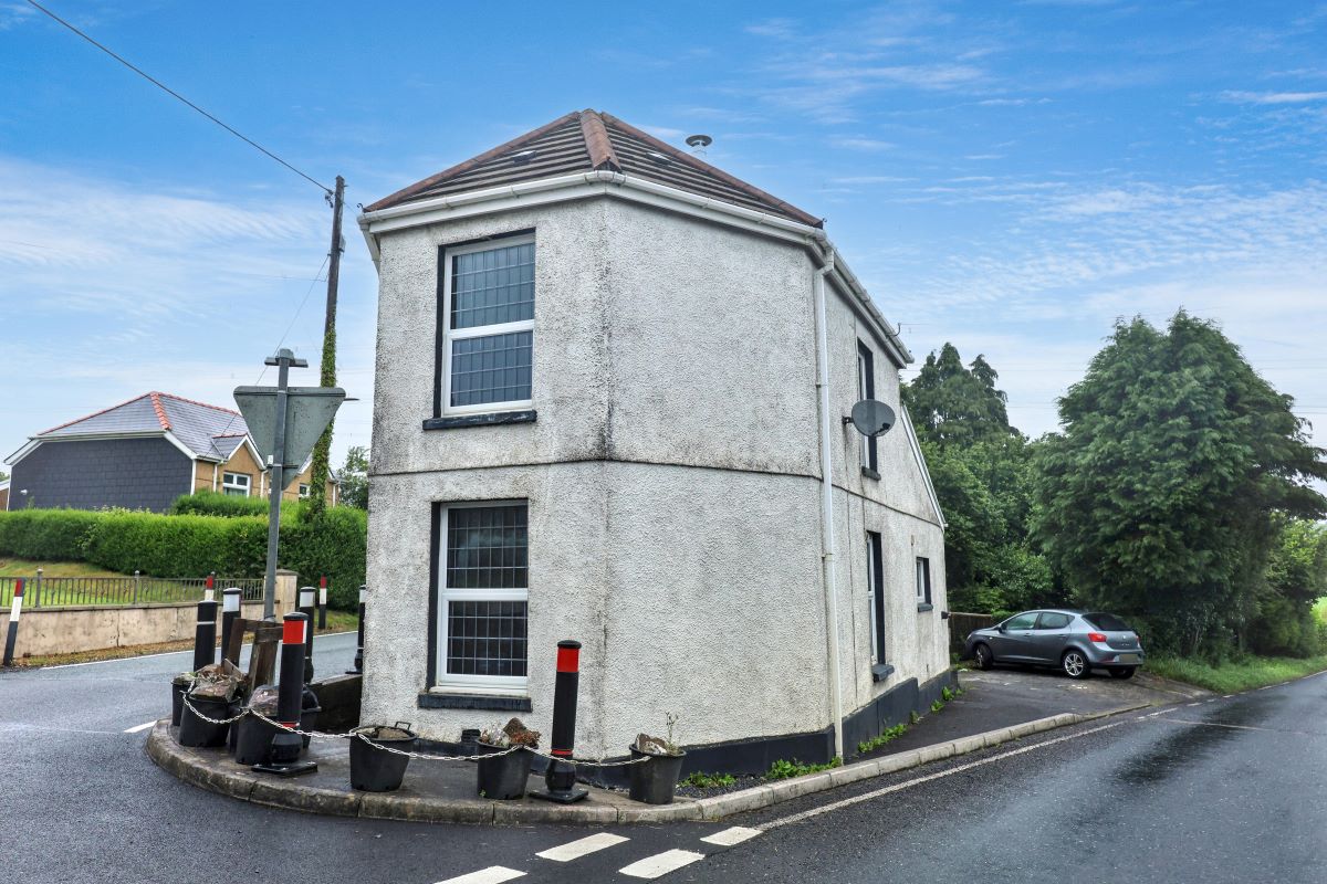 The corner of Gate House in Llannon with bollards, chains and planters guarding its walls from passing traffic