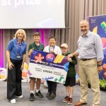 Three Parkland Primary pupils holding a giant first prize cheque, flanked by host Sian Lloyd and DVLA Chief Executive Tim Moss