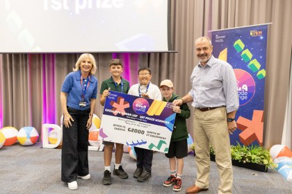 Three Parkland Primary pupils holding a giant first prize cheque, flanked by host Sian Lloyd and DVLA Chief Executive Tim Moss