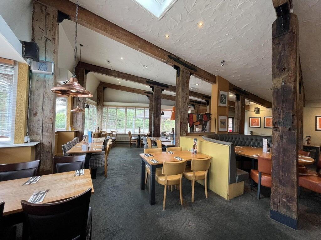 Outdoor seating area at the Bagle Brook with tables and parasols, and the Premier Inn hotel behind