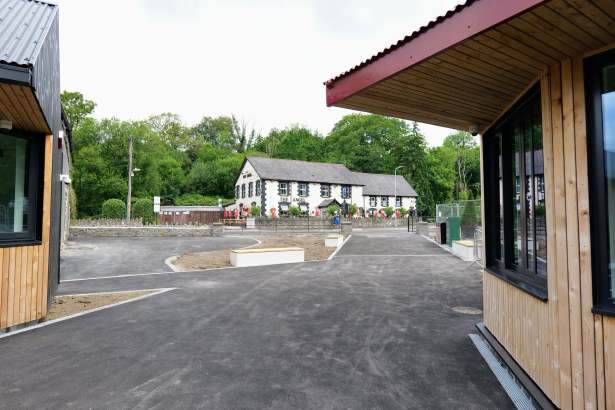 New timber-clad visitor hub buildings at Pontneddfechan with The Angel pub in the background