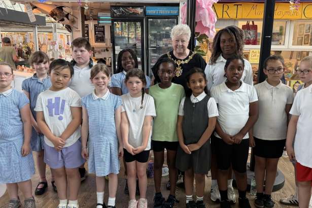 The Lord Mayor of Swansea in her chains of office standing with a group of primary school children in Swansea Market