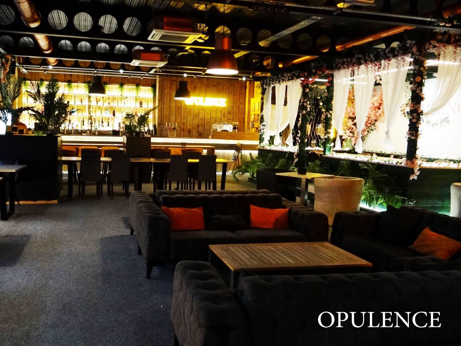 The interior of Opulence in Llanelli, with grey sofas, a lit bar and floral decor