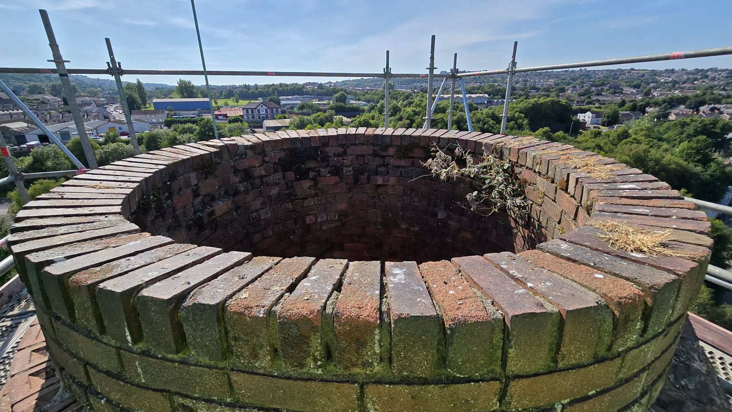 The open brick mouth of the copperworks chimney seen from scaffolding at its summit, with Swansea in the background