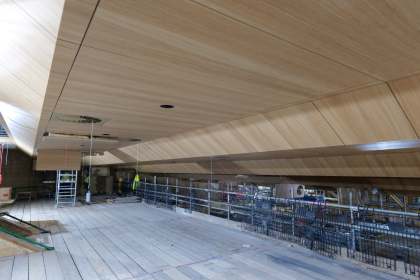 The new angled oak-panelled ceiling installed above the balcony level of the Princess Royal Theatre auditorium, with scaffolding on the construction site below