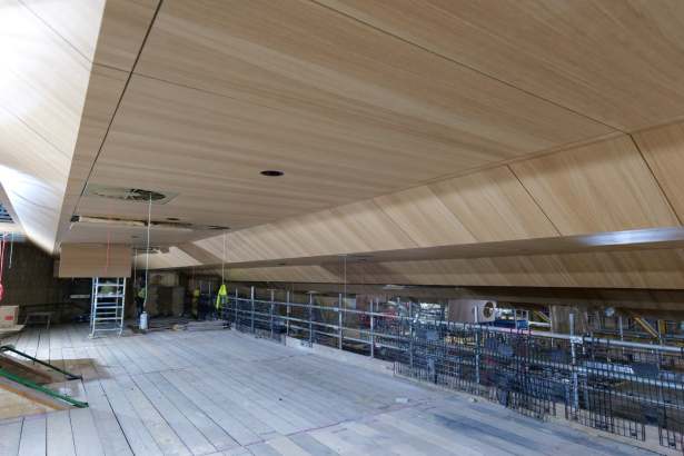 The new angled oak-panelled ceiling installed above the balcony level of the Princess Royal Theatre auditorium, with scaffolding on the construction site below