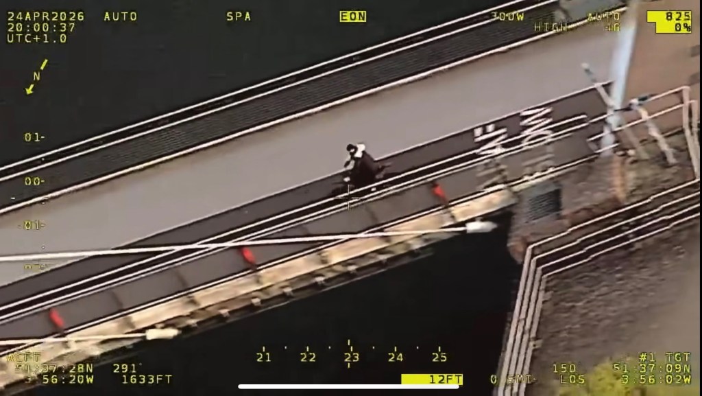 Aerial police camera view of a rider on an electric motorbike crossing a pedestrian footbridge over water