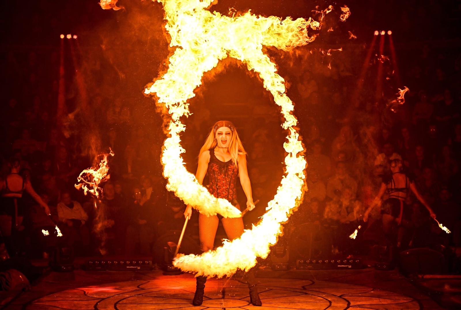 Rebecca Foyle spinning a circle of fire around herself on stage in front of an audience
