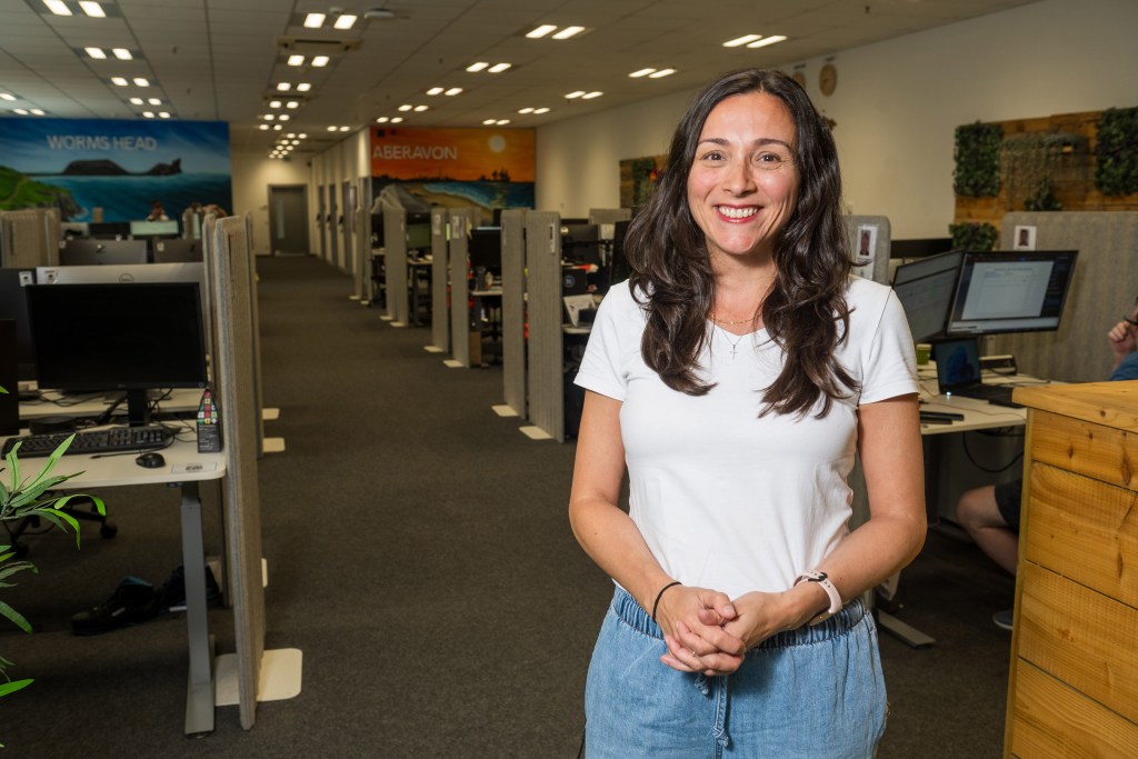 Mariel Ruartes in an office with Worms Head and Aberavon wall murals behind her.