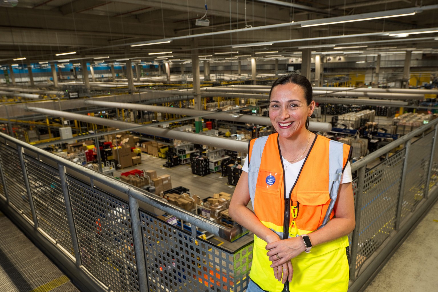 Mariel Ruartes in a hi-vis vest on a walkway above the fulfilment centre floor.