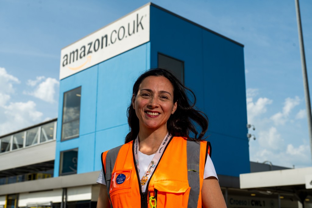 Mariel Ruartes in a hi-vis vest standing outside the Amazon building beneath the amazon.co.uk logo.