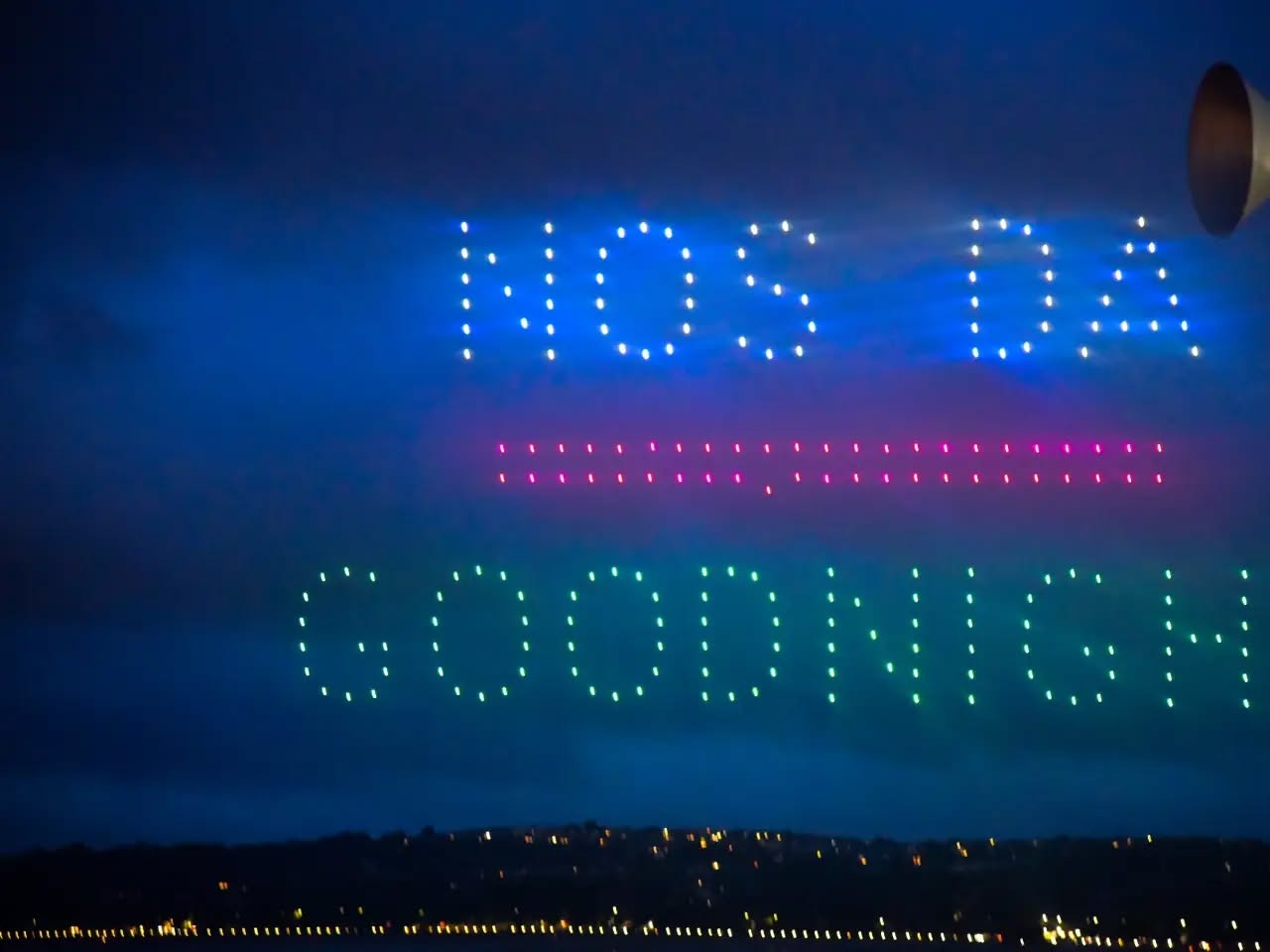 Drones spelling Nos Da above Goodnight in lights over Swansea Bay