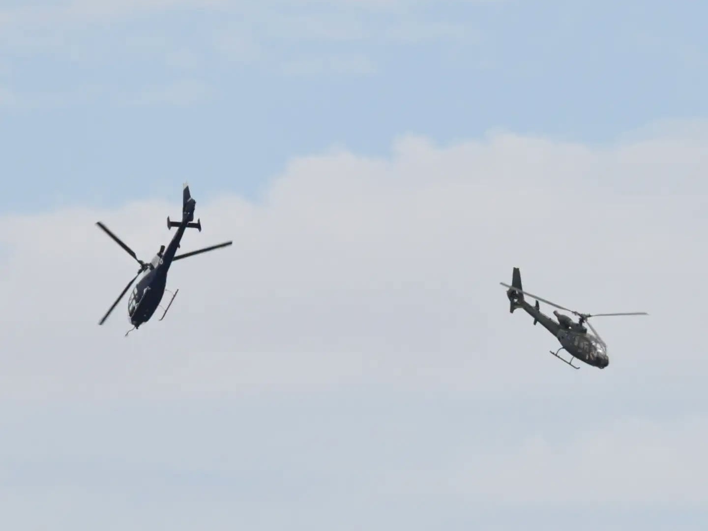 Two Gazelle helicopters flying in formation over Swansea Bay