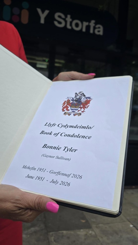 The Bonnie Tyler book of condolence held open outside Y Storfa, showing the bilingual title page and the dates June 1951 to July 2026