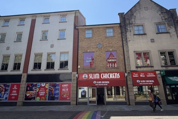 The former Carl's Jr unit on Wind Street, Swansea, with Slim Chickens window vinyls covering the frontage and a rainbow crossing in the foreground, next to the trading Slim Chickens restaurant