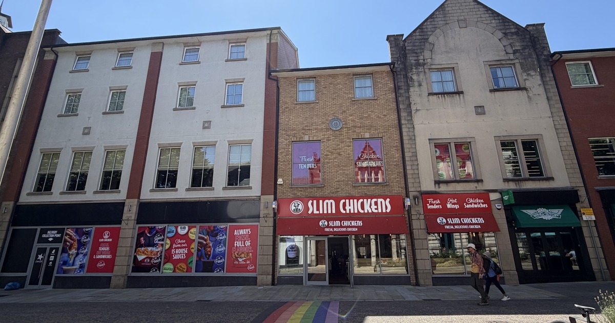The former Carl's Jr unit on Wind Street, Swansea, with Slim Chickens window vinyls covering the frontage and a rainbow crossing in the foreground, next to the trading Slim Chickens restaurant