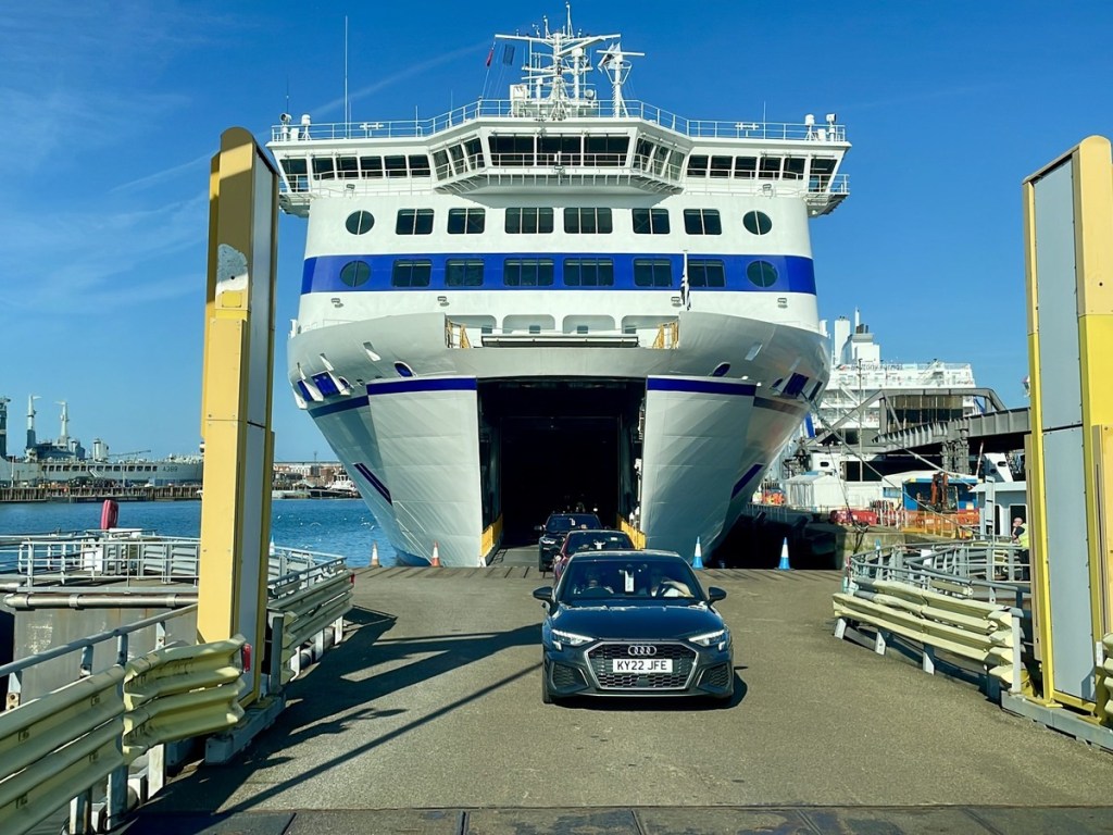 Cars driving off the bow ramp of a large Brittany Ferries ship in port