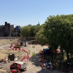 Aerial view of the excavated Castle Square construction site in Swansea, with diggers at work and Swansea Castle in the background
