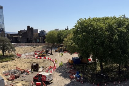 Aerial view of the excavated Castle Square construction site in Swansea, with diggers at work and Swansea Castle in the background