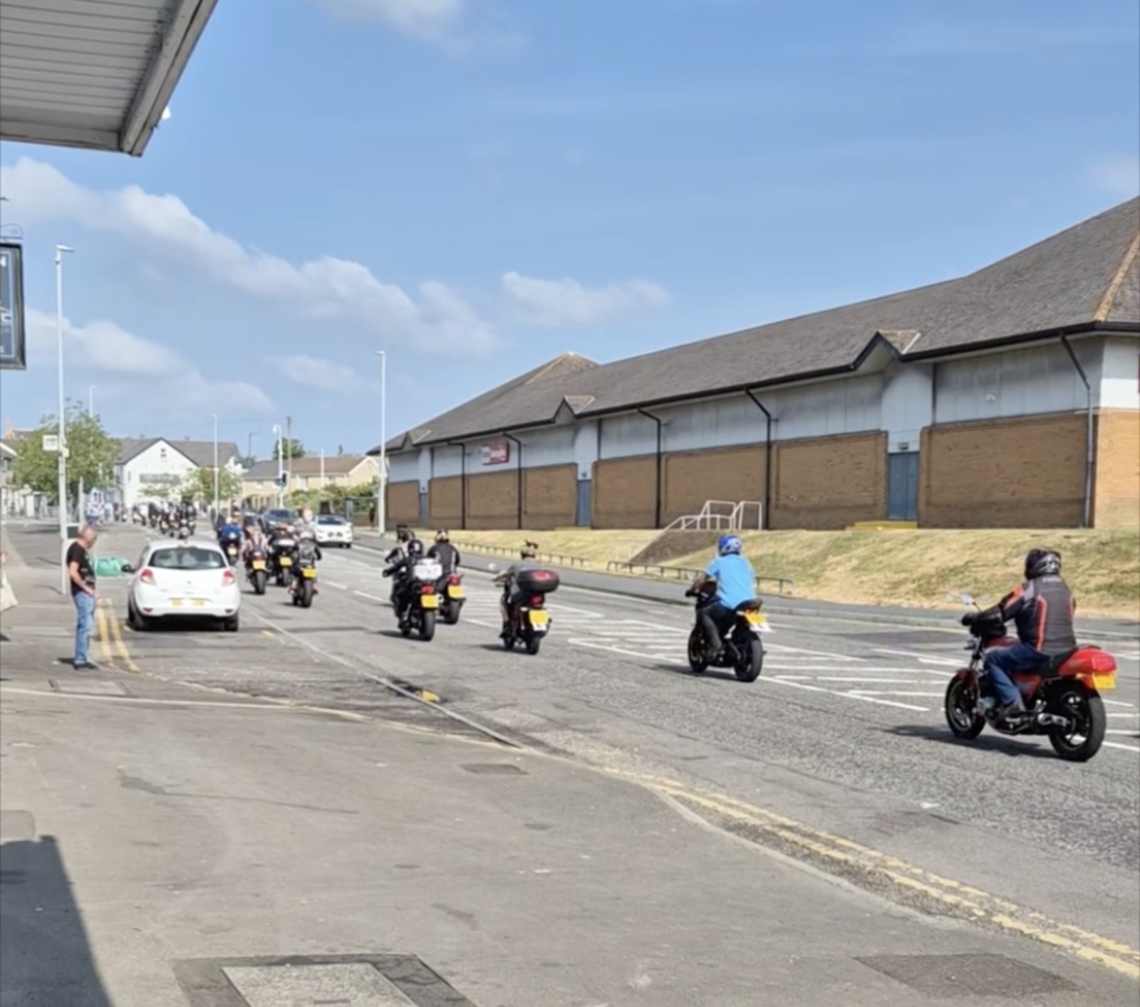 A large group of motorbikes riding down a Gorseinon street watched by onlookers
