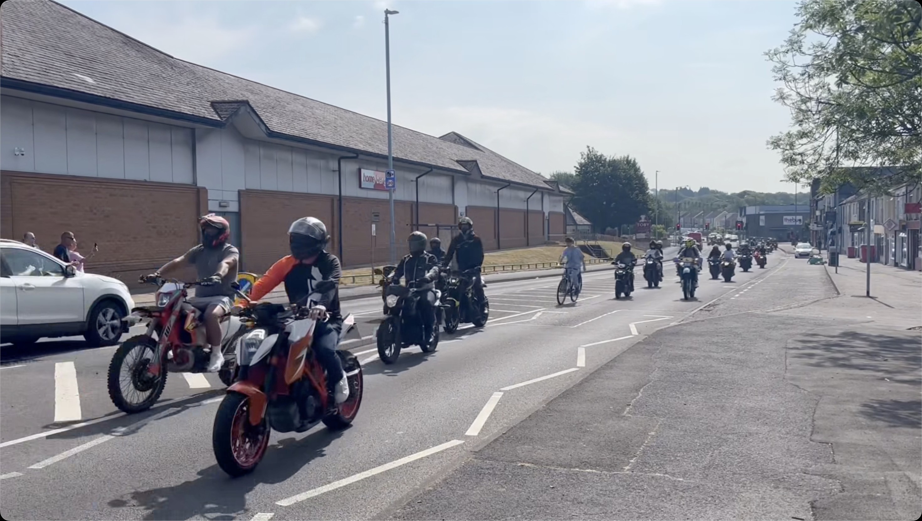 A long line of motorbikes and a quad bike riding past Home Bargains during the ride-out