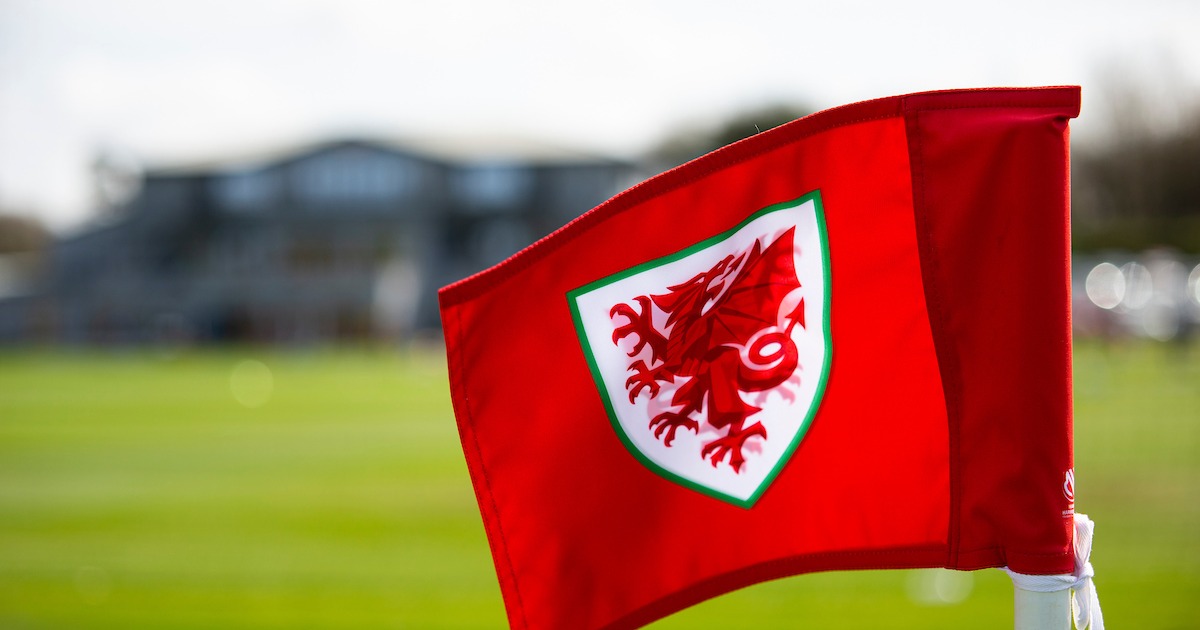 A red corner flag carrying the Cymru dragon crest at the FAW's training ground.