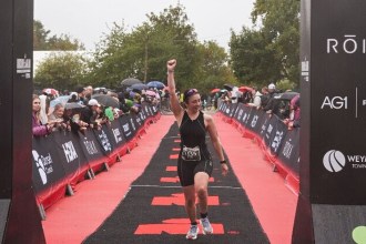 Emily Bond raising her fist as she crosses the IRONMAN 70.3 Weymouth finish line