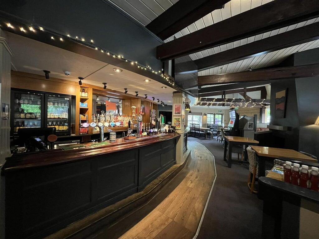 Interior dining area of the Bagle Brook with exposed wooden beams, booth seating and tables laid for service