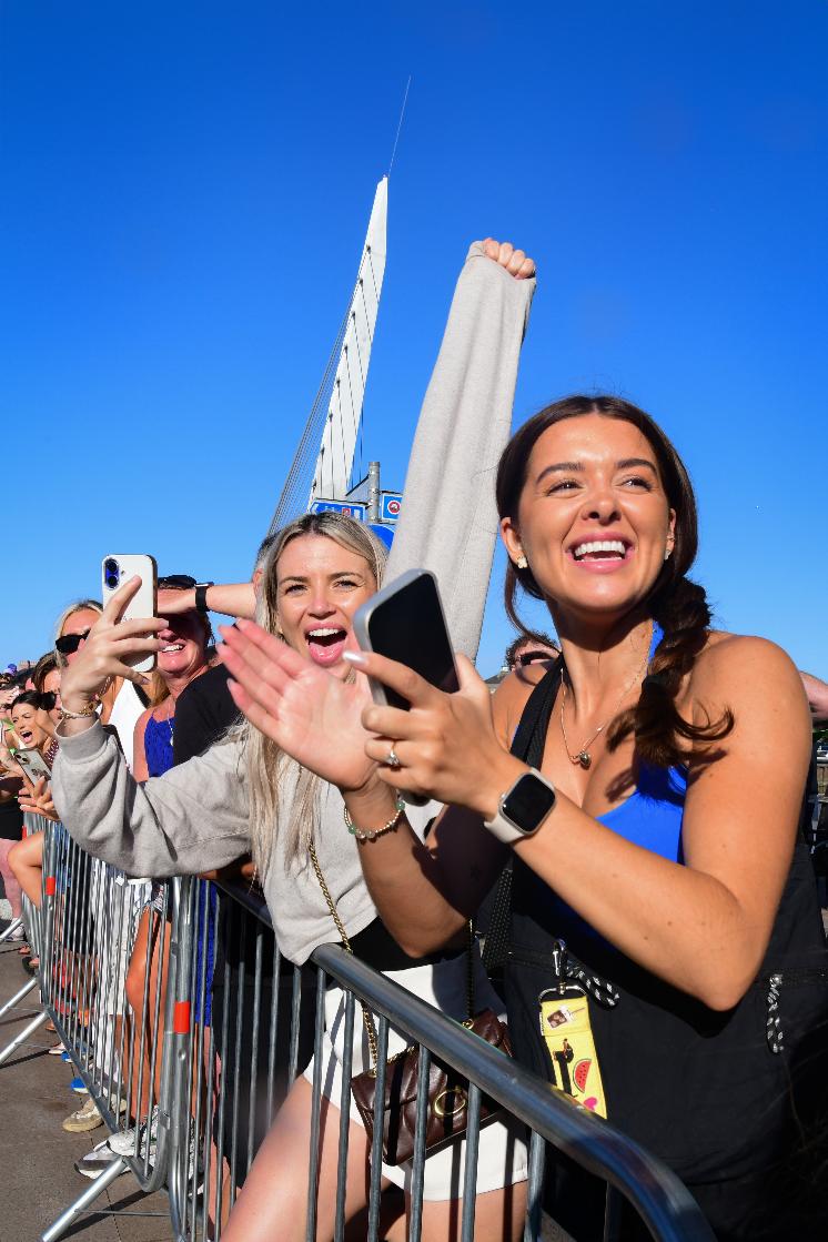 Three women triathletes hold bouquets on the IRONMAN 70.3 Swansea podium, the winner on the number one step flanked by the second and third-placed finishers