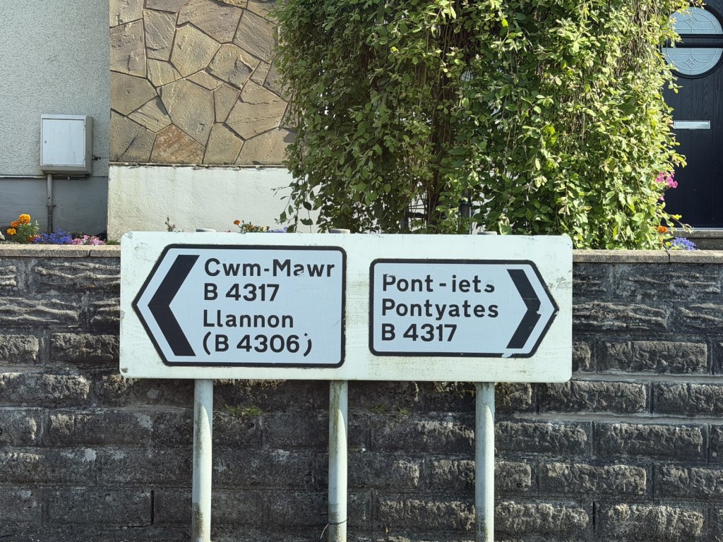 A road fingerpost showing directions to Cwm-Mawr and Llannon on the B4306, and Pont-iets and Pontyates on the B4317.