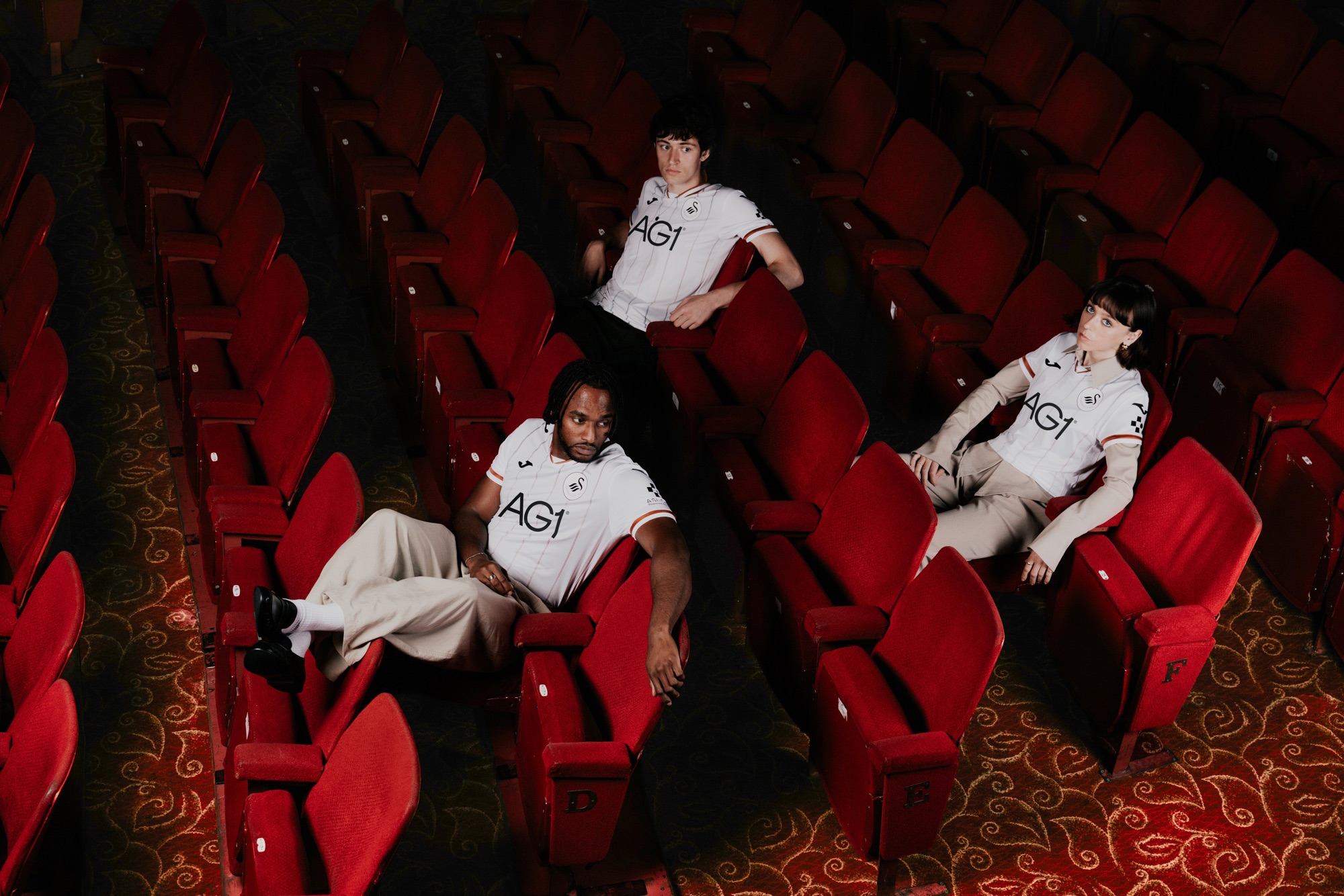 Three models in the new Swansea City home shirt in the stalls of the Grand Theatre