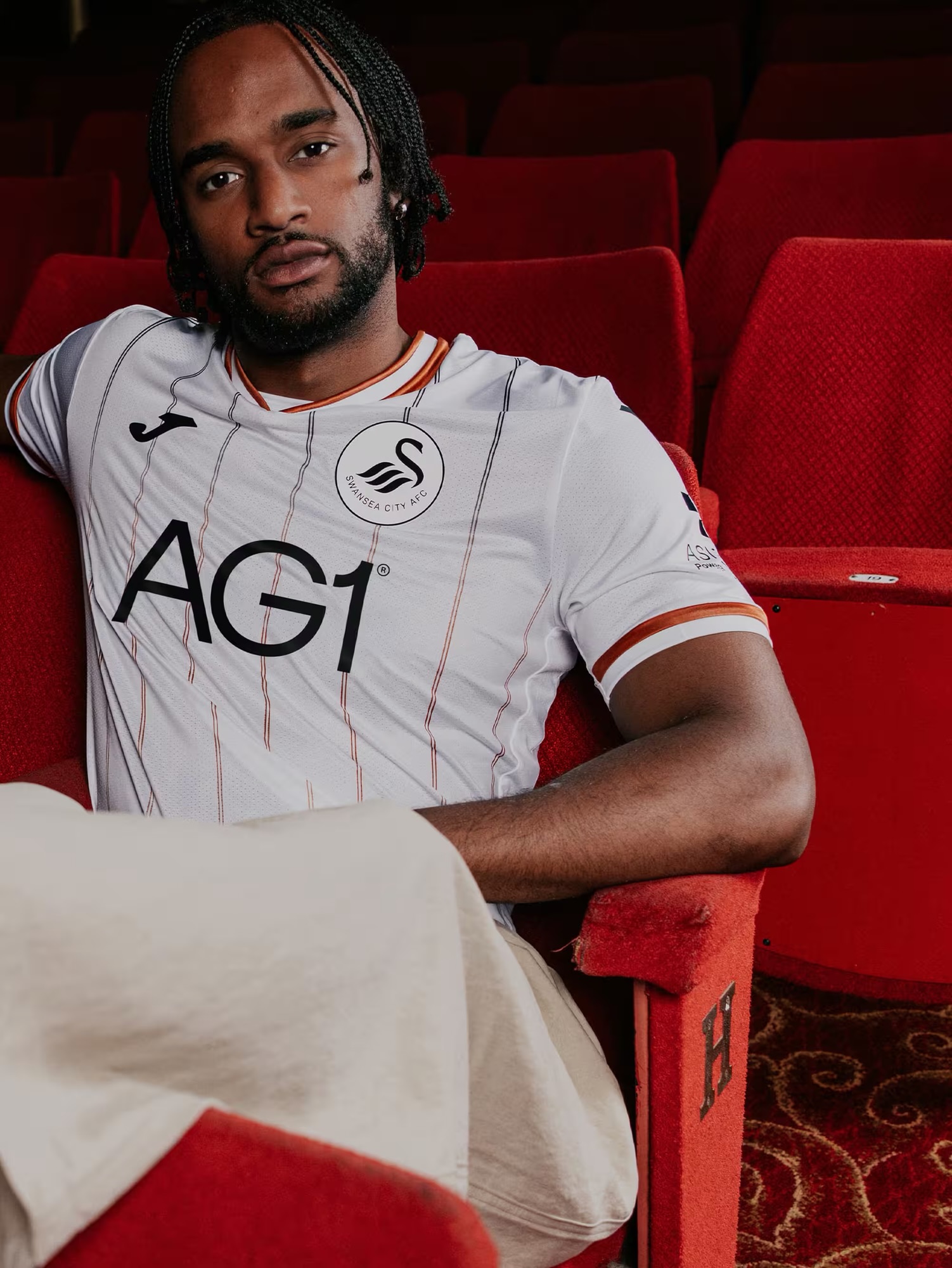 A model in the new Swansea City home shirt among the Grand Theatre's red seats