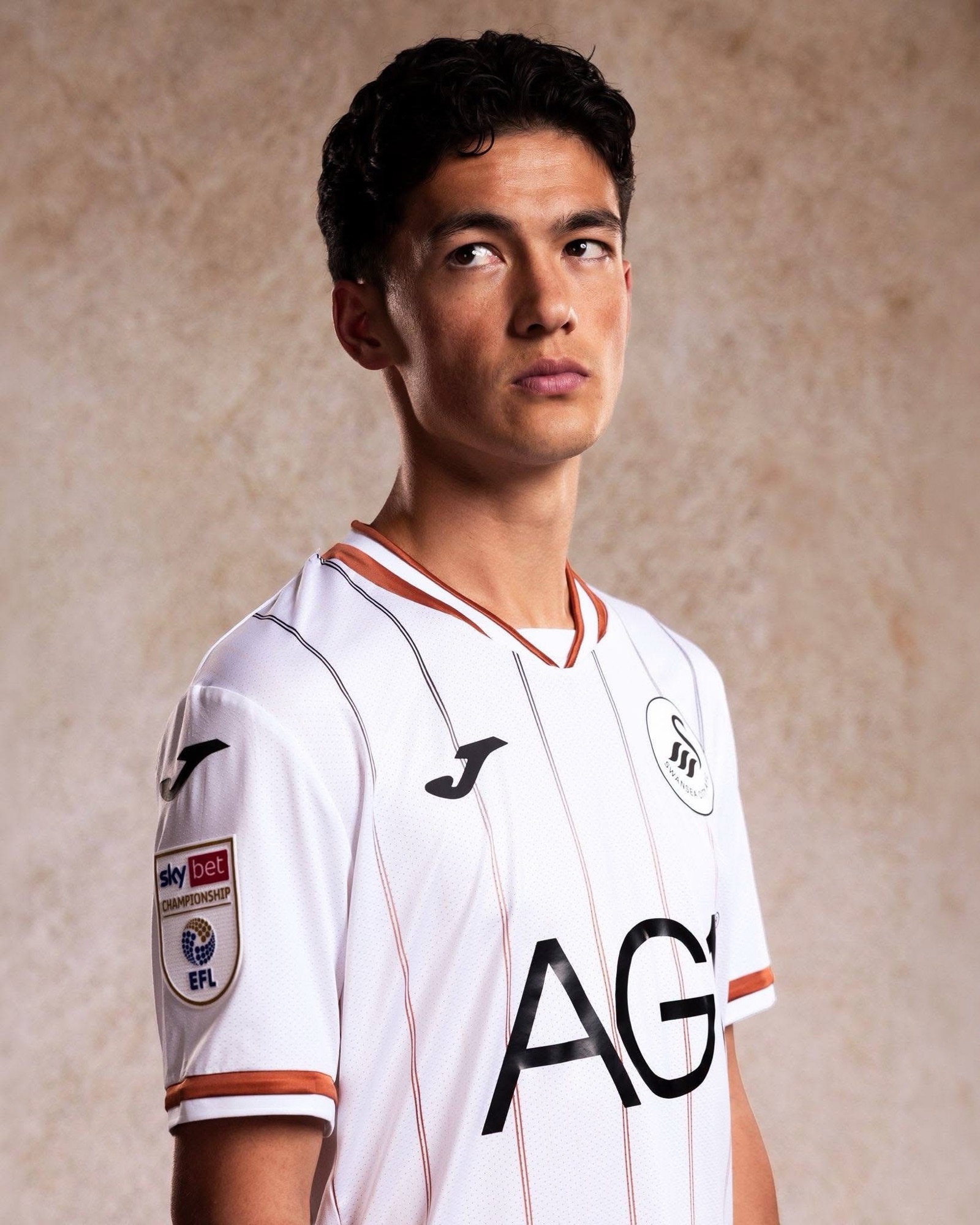 Close-up of the new Swansea City home shirt showing copper and black pinstripes and the Sky Bet Championship sleeve badge