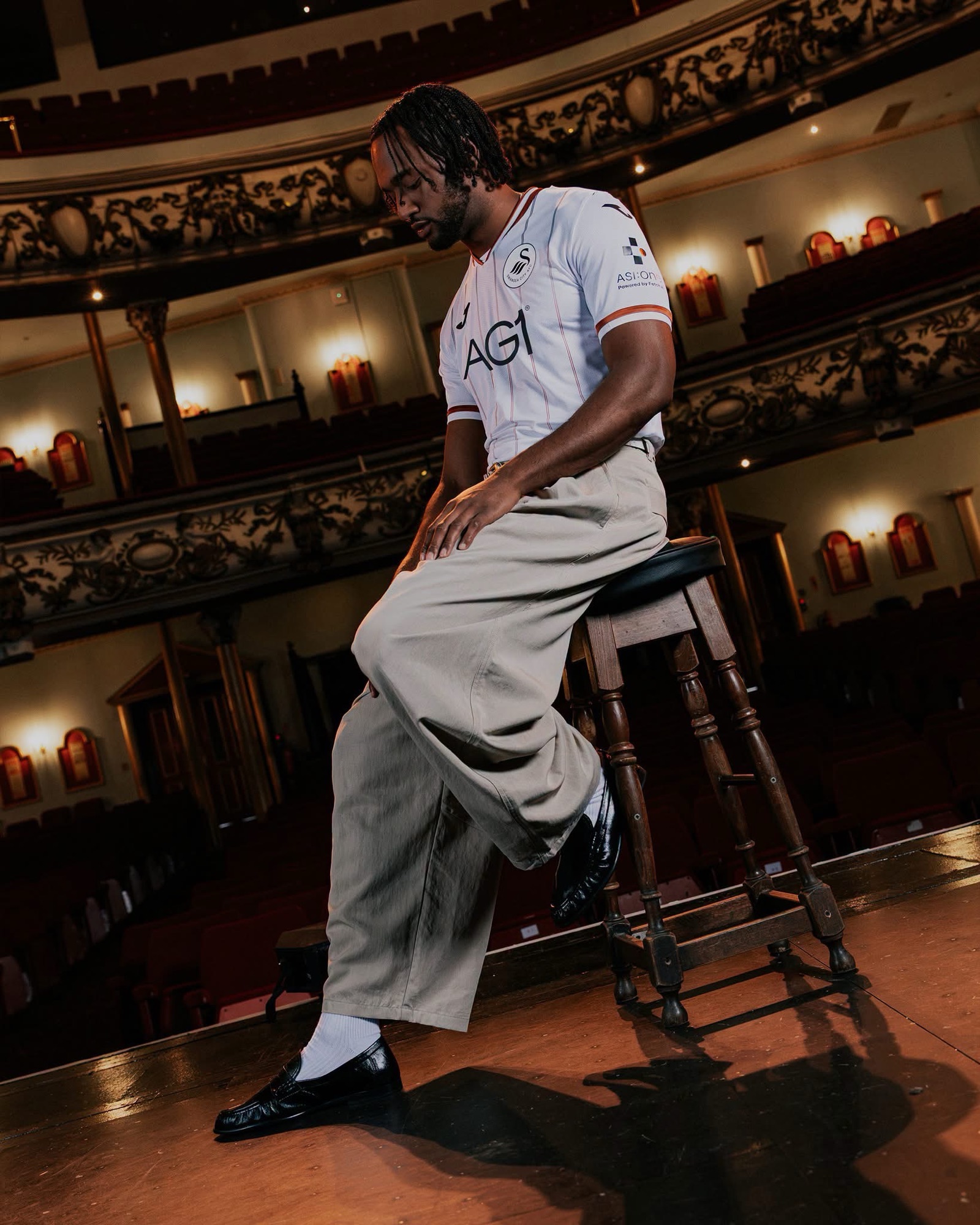 A model in the new Swansea City home shirt sitting on a stool on the Grand Theatre stage