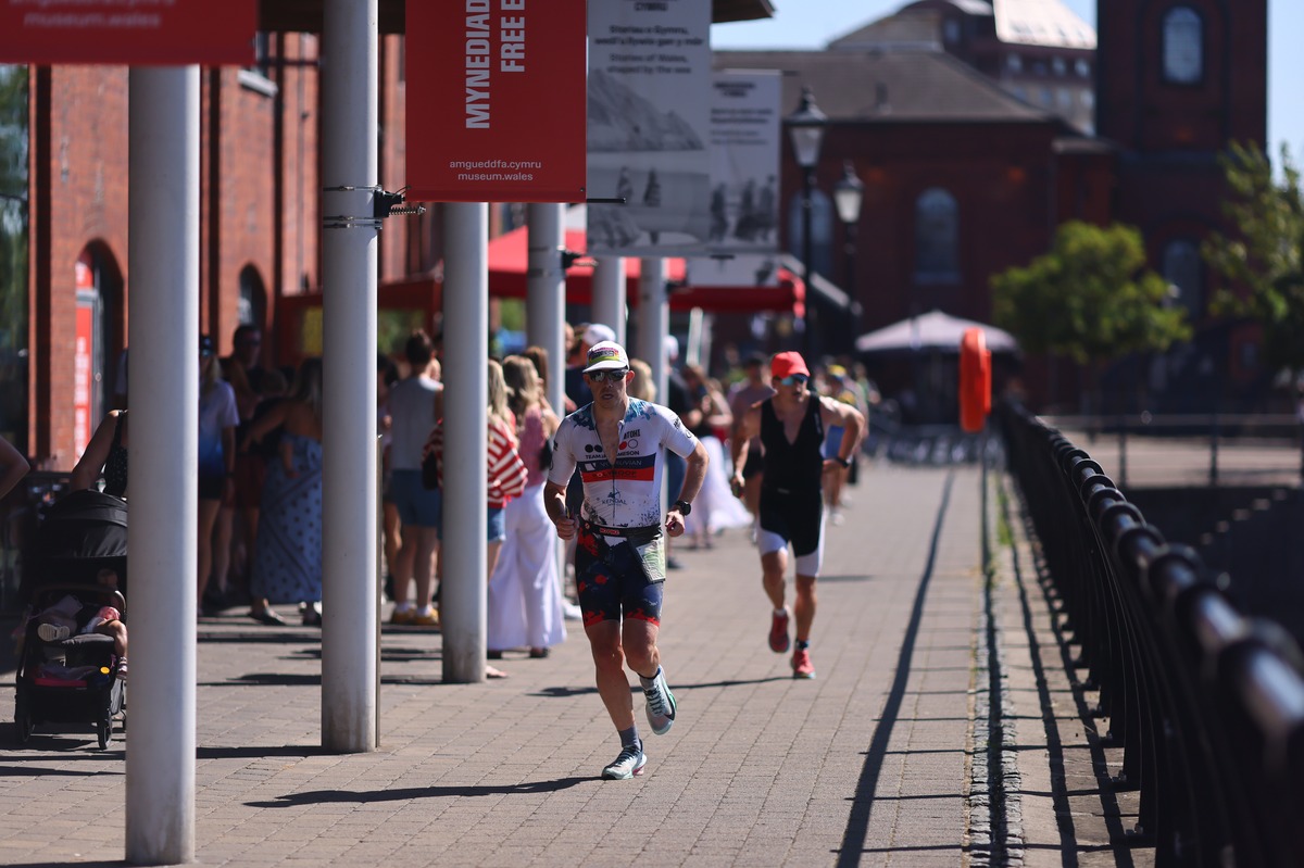 A runner in SVT club kit emerges from a red-brick archway into sunshine
