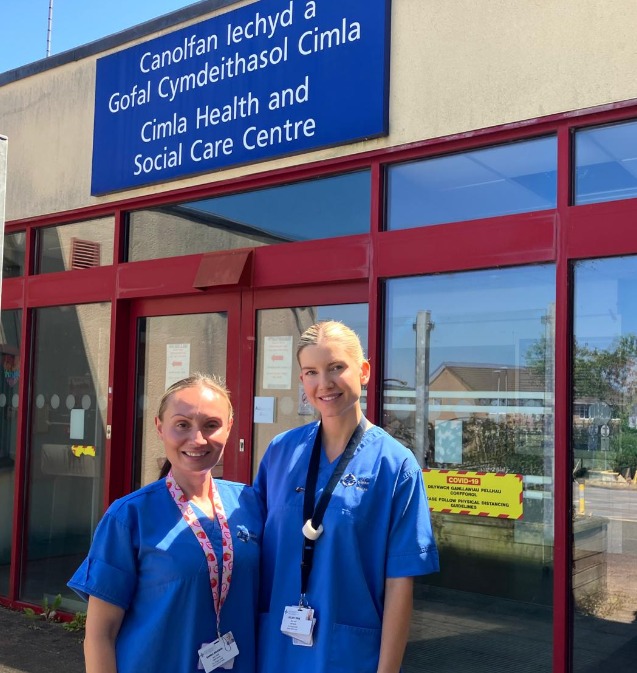 Nurses Kelsey Pirie and Emma Brown in blue uniforms outside the Cimla Health and Social Care Centre