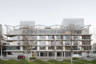The exterior of 71/72 Kingsway in Swansea city centre, a multi-storey glass and concrete commercial building fronted by trees and a green space on The Kingsway